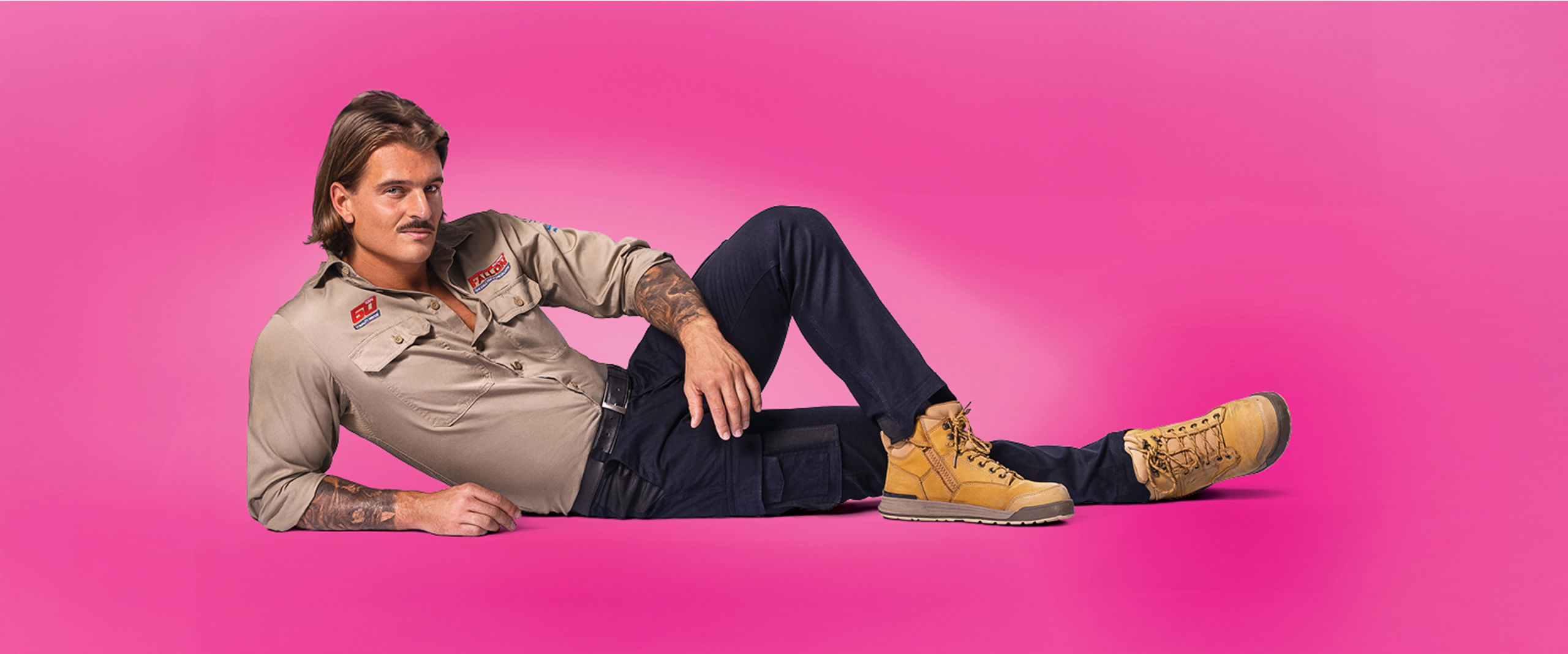 A stylish model showcasing Creative Outpost's rugged workwear against a vibrant pink background.