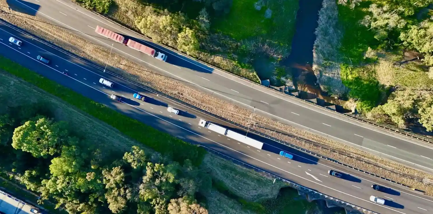 Aerial view of vehicles on a highway surrounded by greenery and waterways.