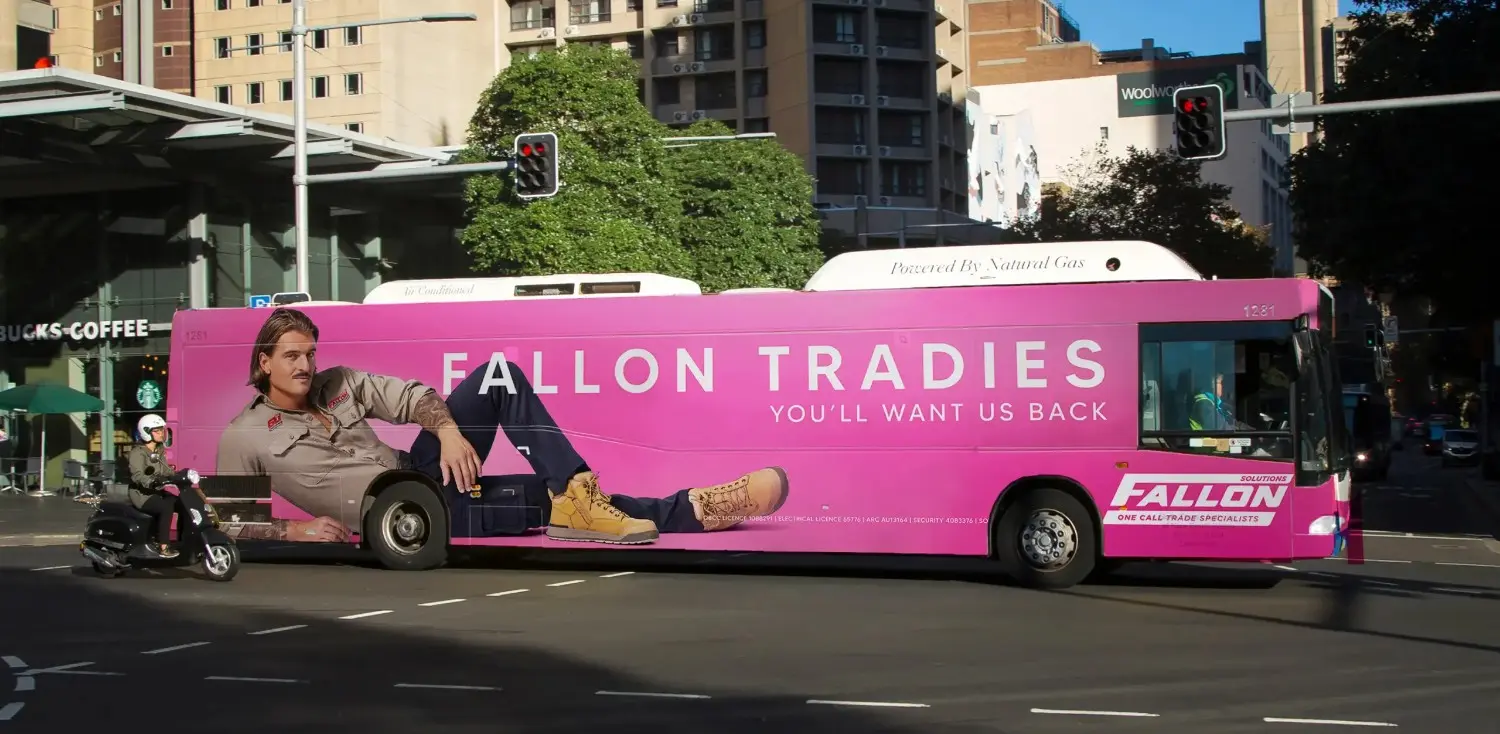 Brightly colored bus advertisement for Fallon Tradies campaign in an urban setting.