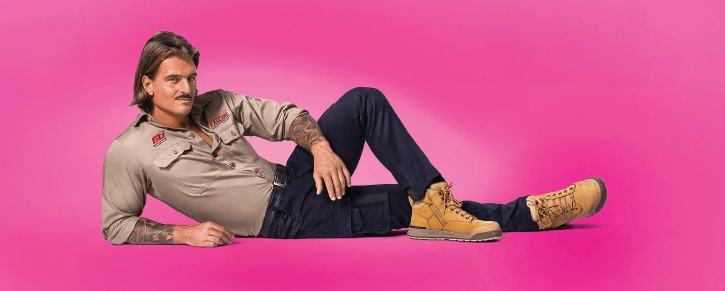 Creative Outpost brand model confidently poses in stylish workwear against a vibrant pink background.