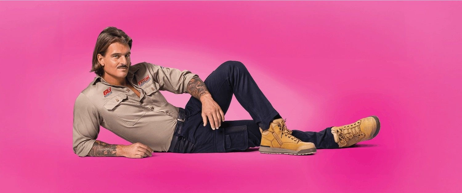 Creative Outpost brand model confidently poses in stylish workwear against a vibrant pink background.